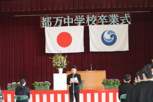 体育館正面で生徒の代表として、挨拶を行う男子生徒の写真