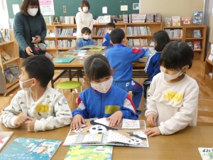 図書室で一つの本を互いに見ながら一緒に読書をする児童たちの写真