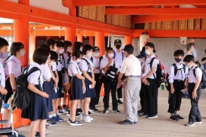 神社の回廊で児童たちが案内人の話を聞いている写真