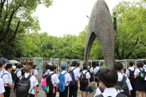 修学旅行に来た児童たちが慰霊碑の前で集まっている写真