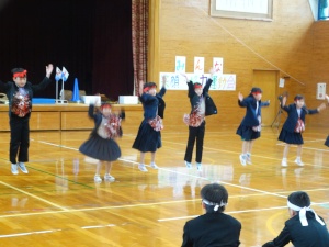 赤いハチマキをした児童たちが両手を挙げて飛び跳ねている写真