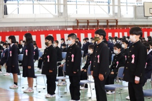 紅白幕に囲まれた体育館に立つ新入生の写真