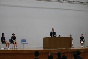 舞台上の教壇の前に立ち発表している生徒の写真