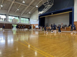 体育館の半面のバスケットコートでプレイする生徒たちの写真