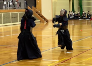 体育館で剣道着を着て一歩踏み出し勝負をしている生徒たちの写真