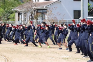 グラウンドで赤いメガホンを構えて応援している生徒たちの写真
