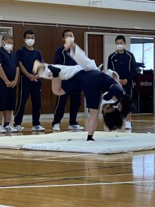 体育館に敷かれたマットの上で背負い投げをする生徒の写真