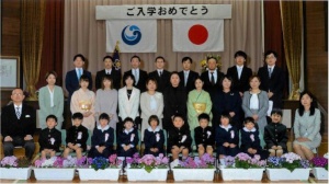 体育館の壇上で新入生と保護者が並び記念撮影をしている写真