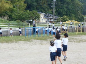 校庭で遊具を使って遊ぶたくさんの児童たちの写真