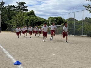 校庭で児童たちが全力で走っている写真