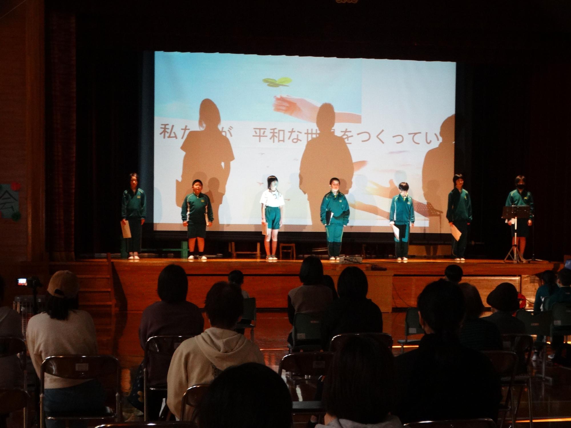 緑のジャージを着た児童が間隔をあけて立ち出し物をしている写真