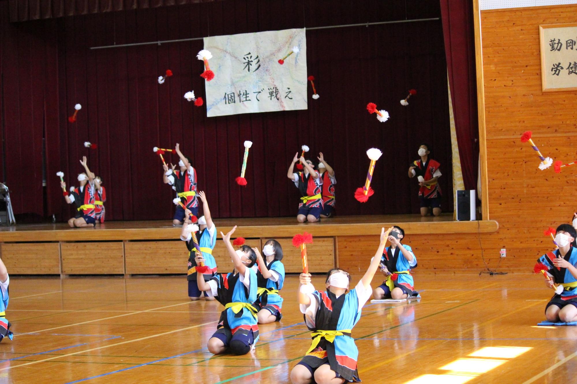 はっぴを着た生徒たちが紅白の棒を投げている写真