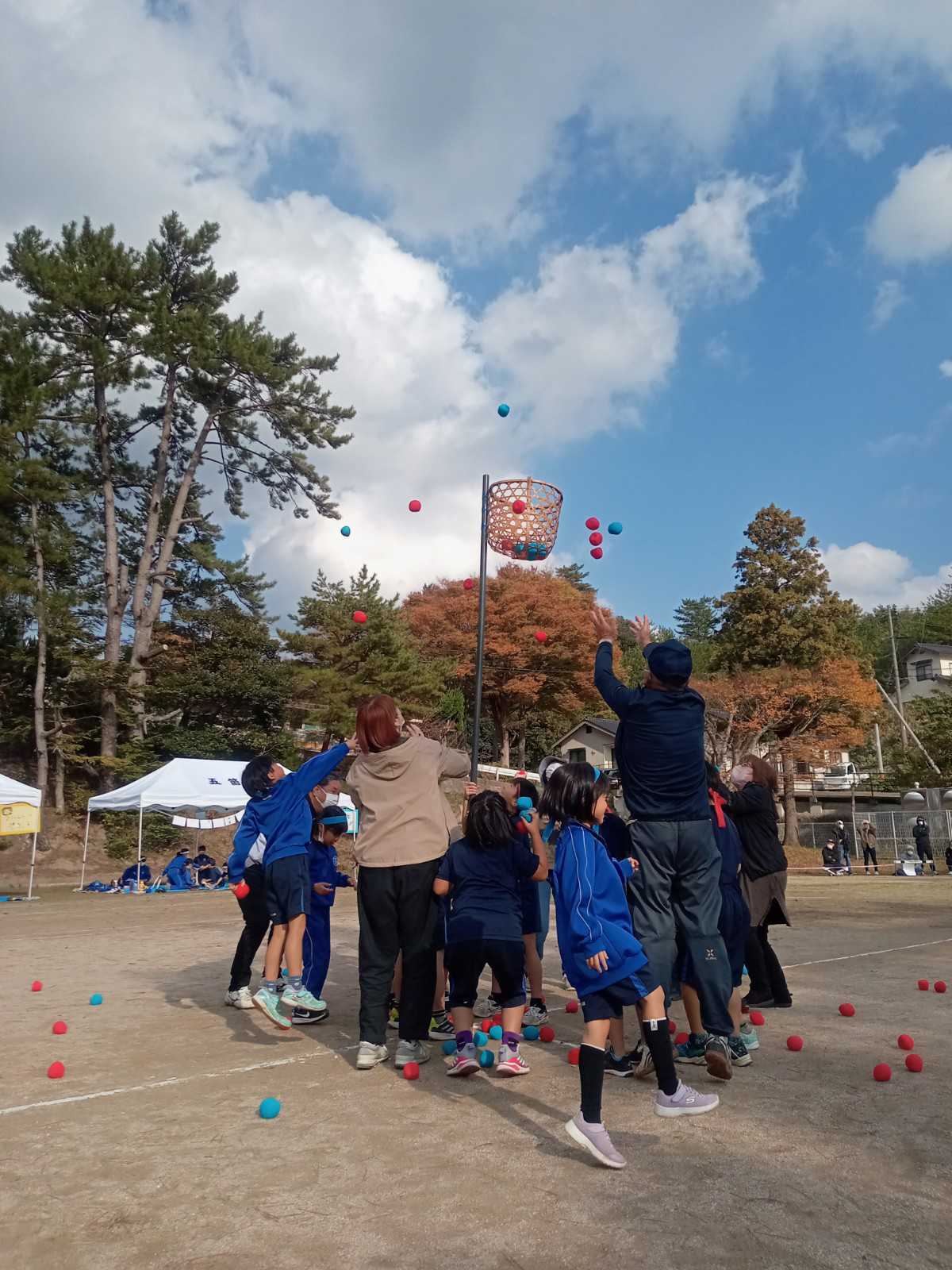 校庭で児童と保護者が玉入れをしている写真
