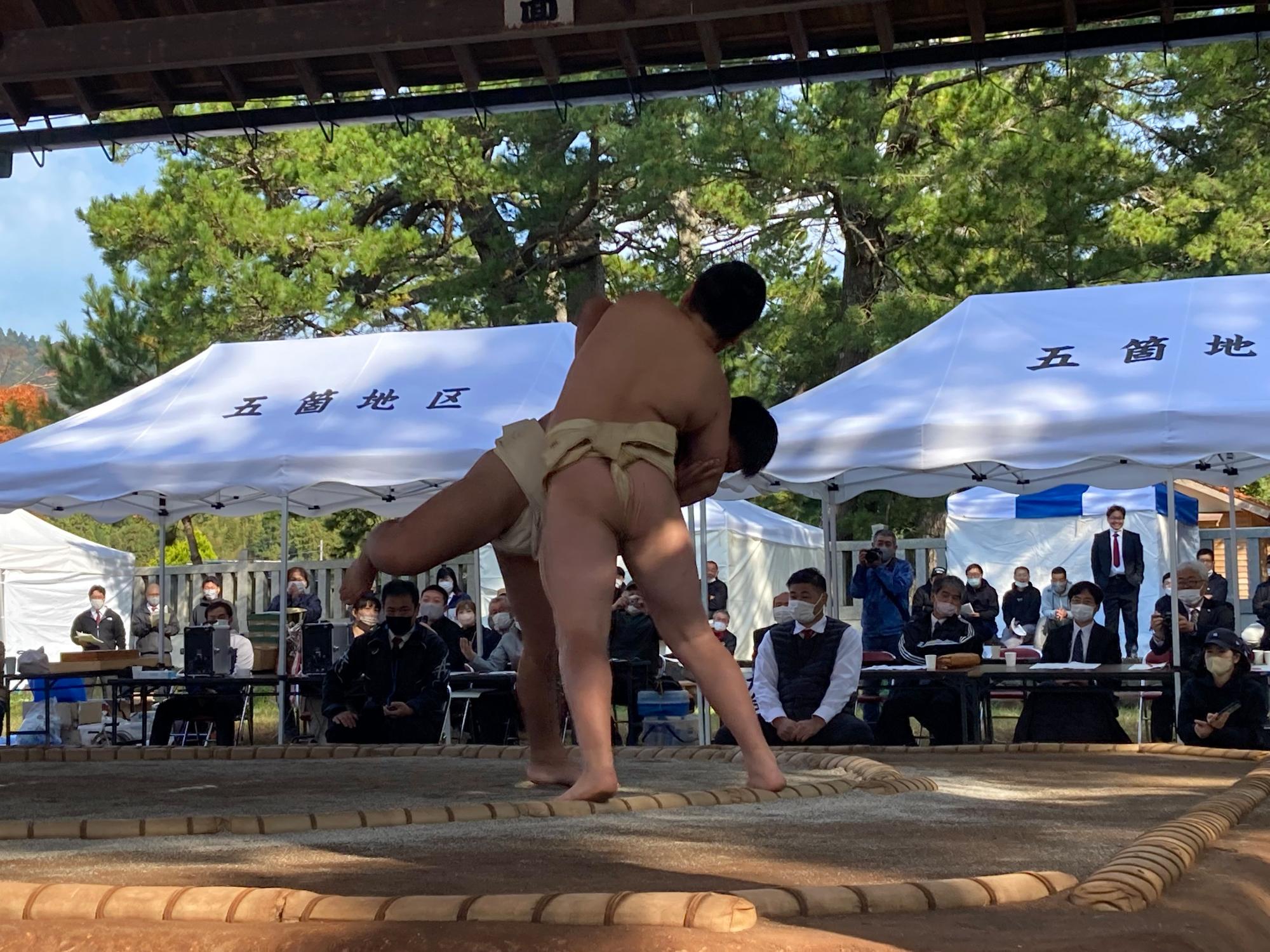 相撲大会で児童が土俵の端で投げ合っている写真