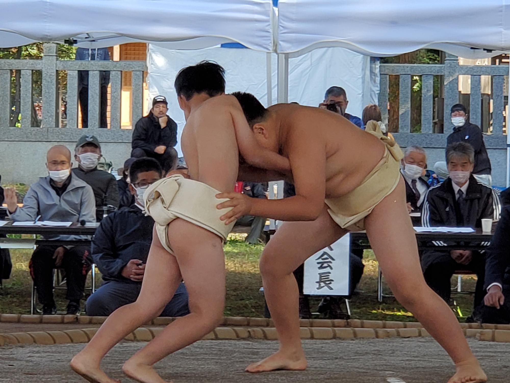 相撲大会で児童が土俵の中央で組み付いている写真