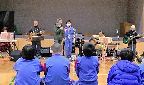 体育館で地域の人たちと児童が一緒に演奏を楽しんでいる写真