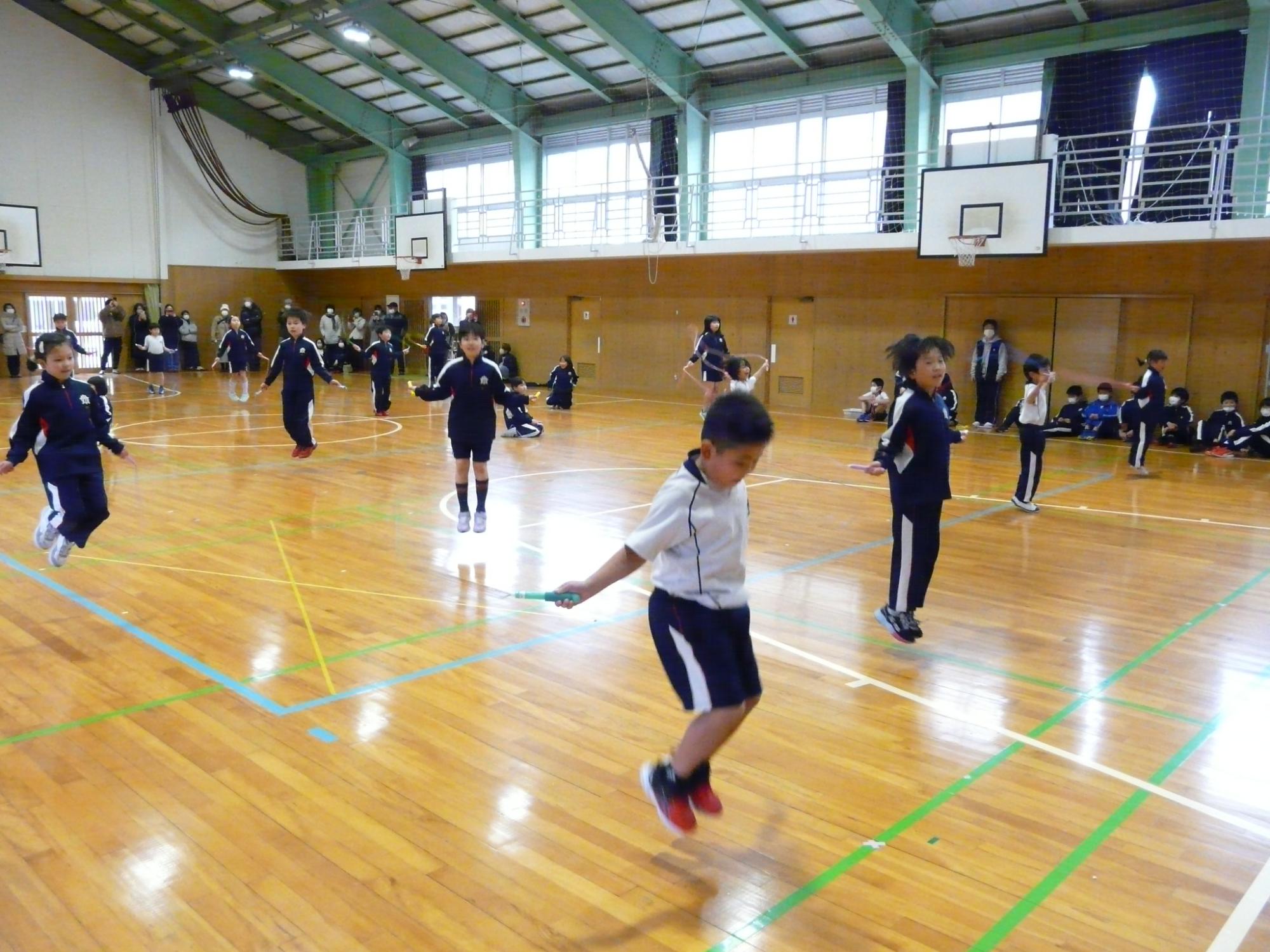 体育館で間隔を広く開けて縄跳びをする児童たちの写真
