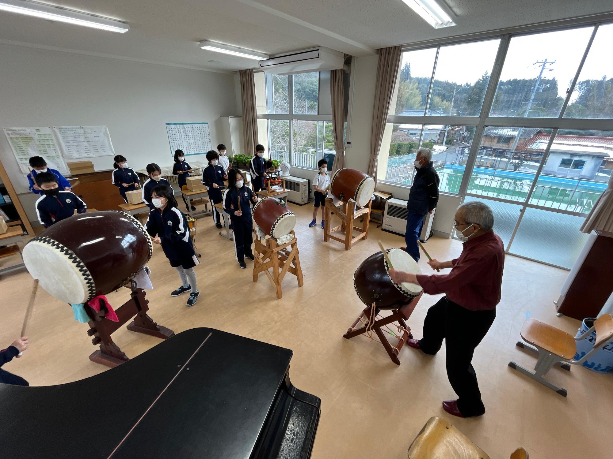 音楽室で和太鼓をたたく児童たちの写真
