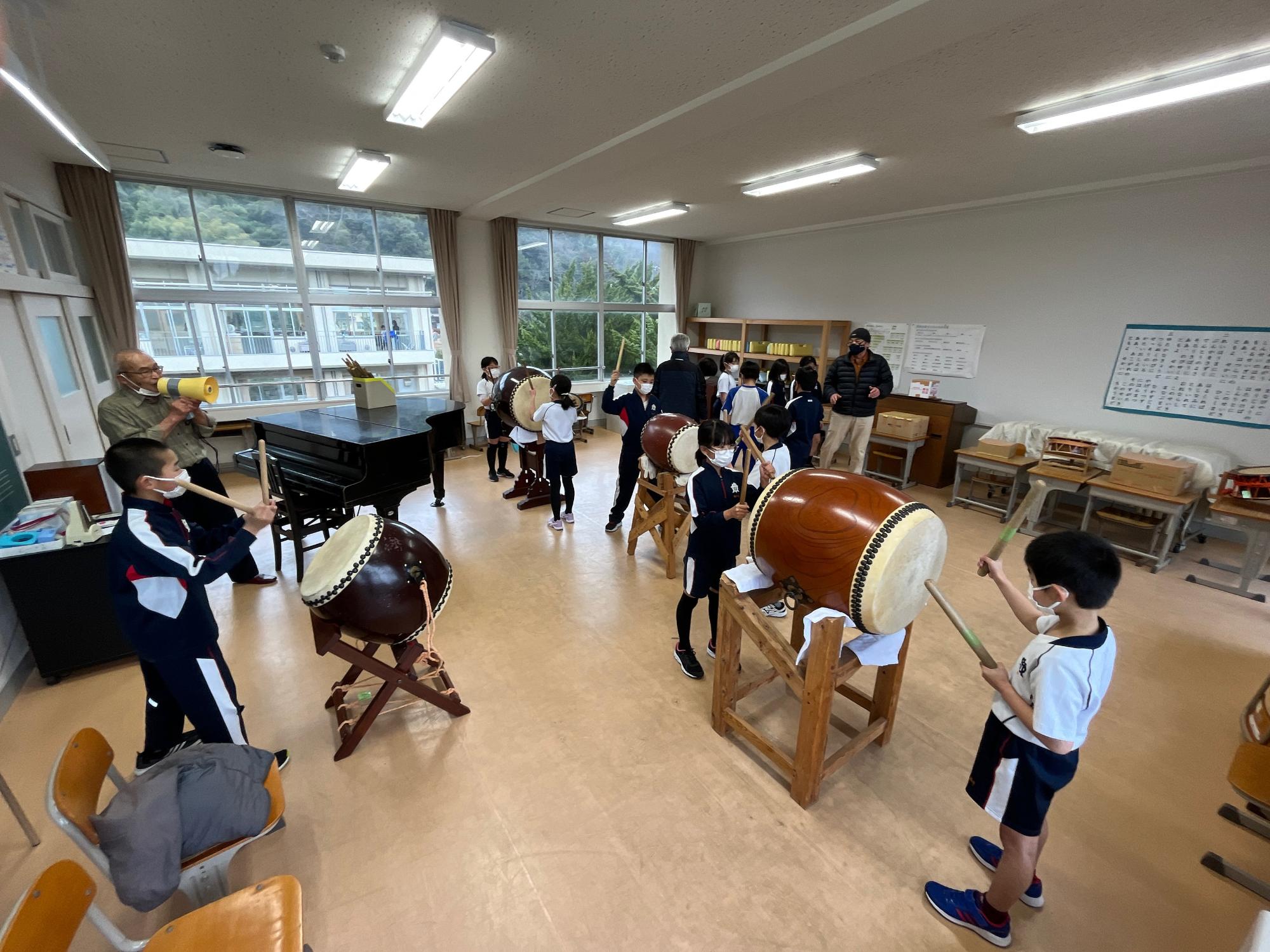 音楽室で和太鼓をたたく体操着を着た児童たちの写真