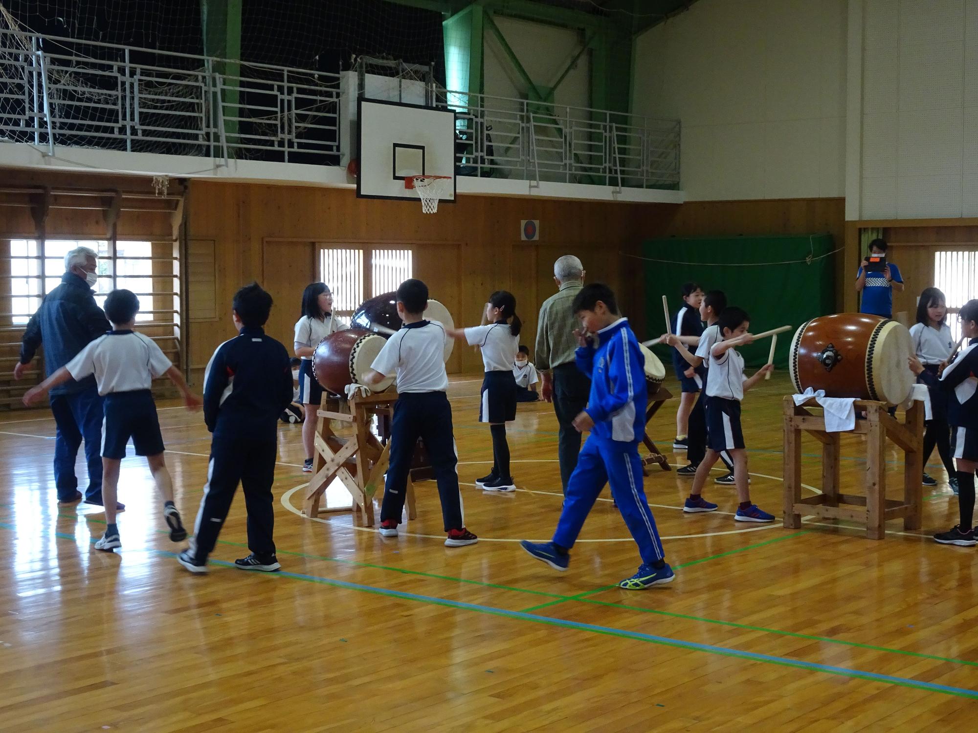 体育館で和太鼓をたたく児童たちの写真