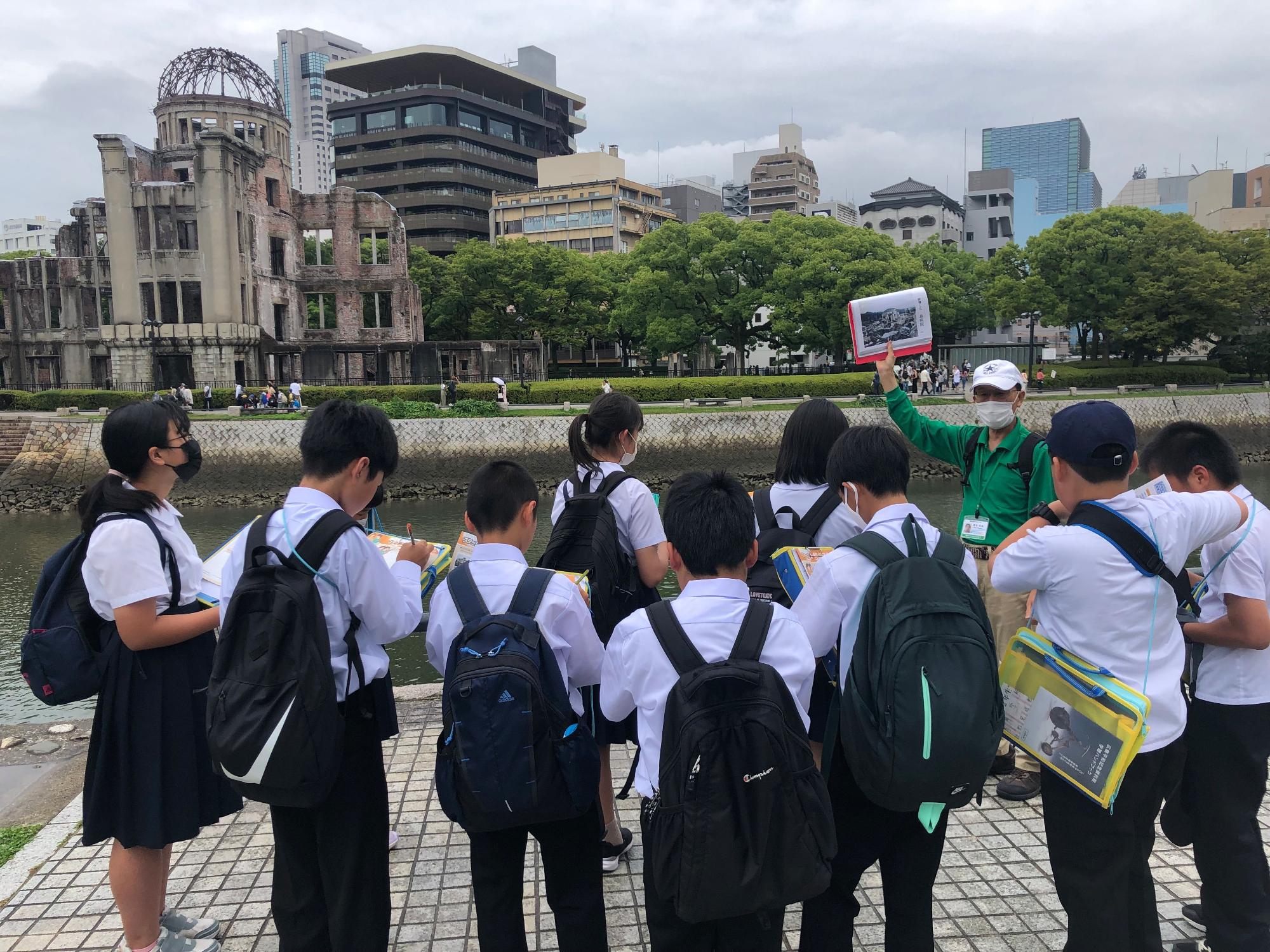 修学旅行にきた児童たちがガイドさんの案内を受けている写真