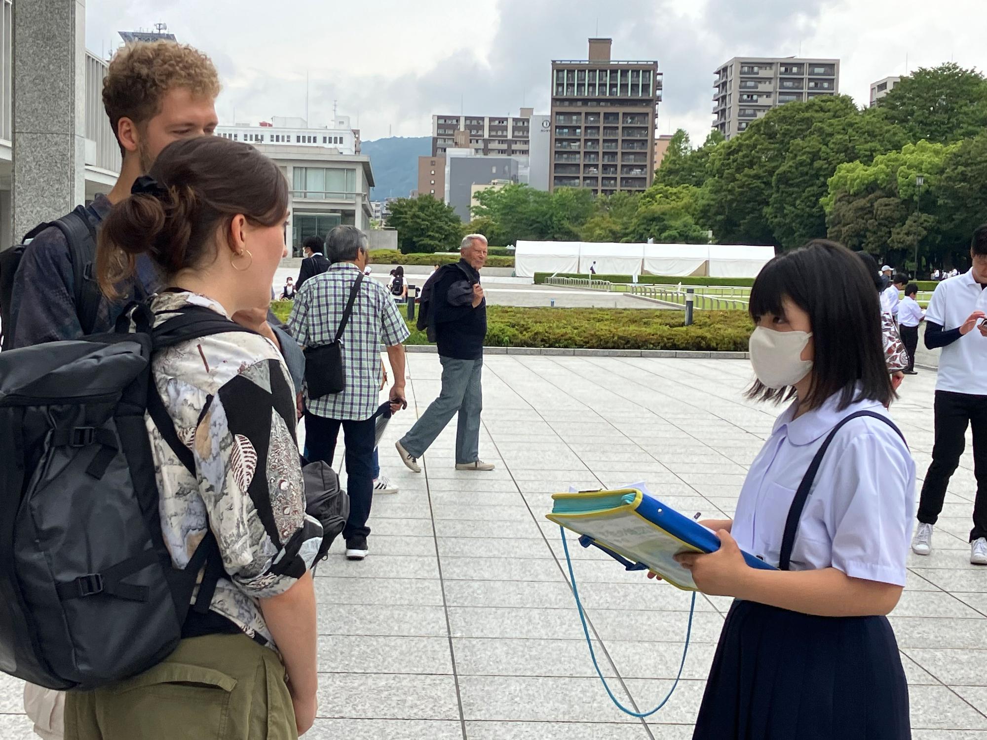 修学旅行にきた児童が2人の外国人にインタビューをしている写真