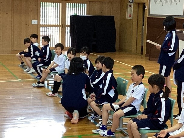 体育館で上級生がしゃがみ込み椅子に座っている下級生にインタビューをしている写真