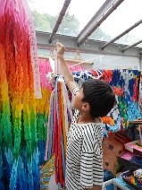 片手をあげて虹色の折り鶴の束を見上げる児童の写真