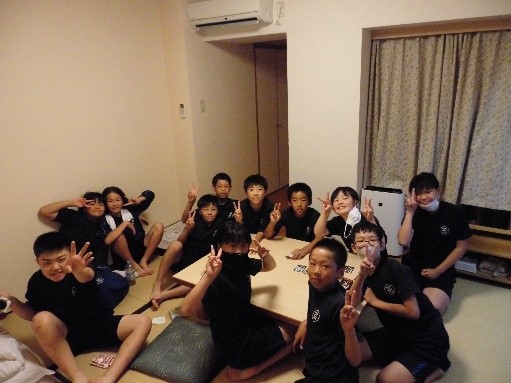 宿泊学習の和室の部屋でくつろぎながら笑顔を見せる児童たちの写真