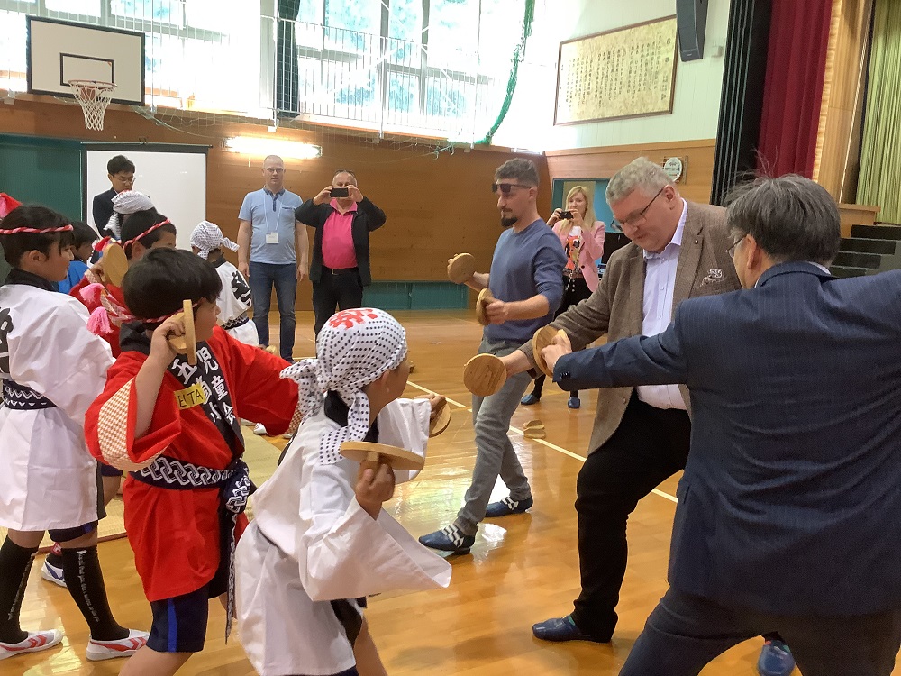 体育館で外国人と法被を着た児童が一緒に郷土芸能の練習をしている写真