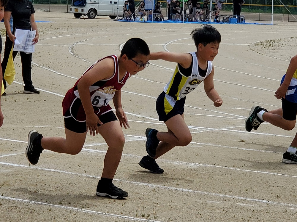 グラウンドのトラックでスタートダッシュをする児童たちの写真