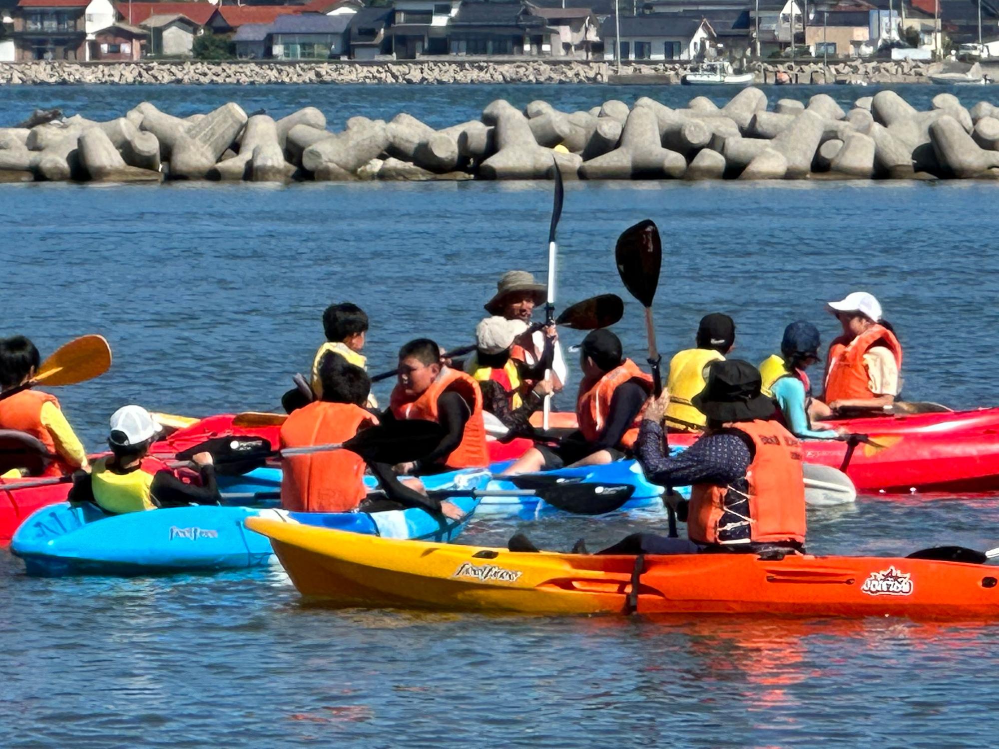 海辺でライフジャケットを着てカヌーをしている児童たちの写真