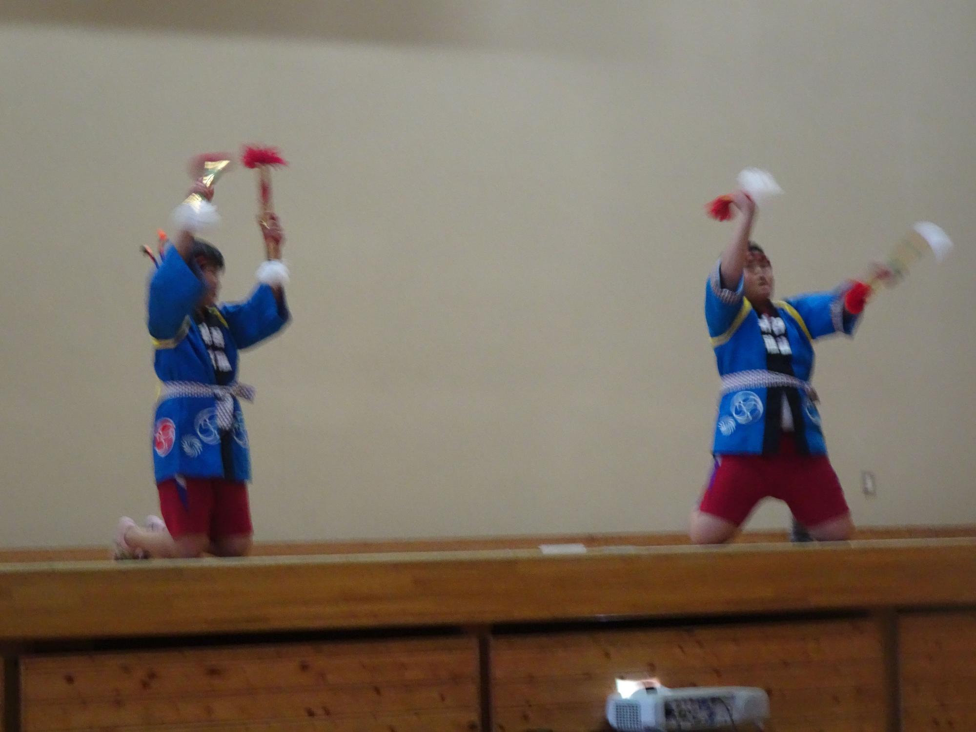 ステージで法被を着た児童が舞を披露している写真