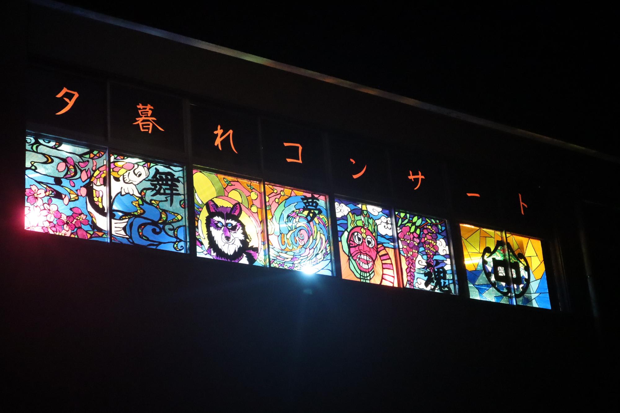 校舎の窓に貼られたステンドグラス風の装飾がライトアップされた写真