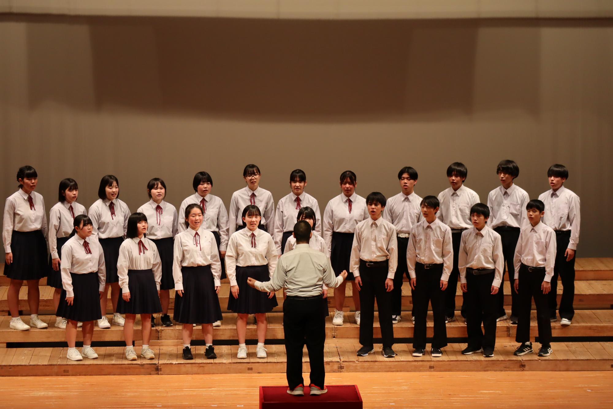 ステージ上で男女の生徒たちが合唱をしている写真