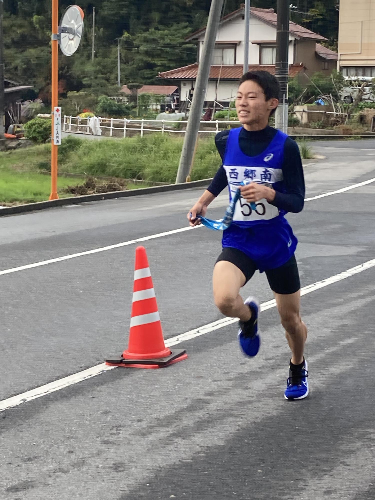 道路沿いでゼッケンをつけた男子生徒が力走している写真
