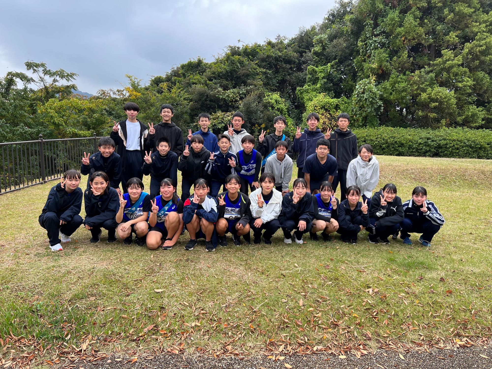 芝生の上でユニフォーム姿の生徒たちが集合して記念撮影をしている写真