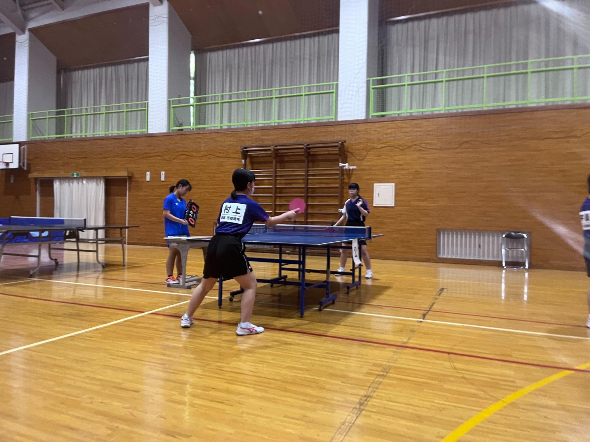 体育館で卓球の試合をしている生徒たちの写真