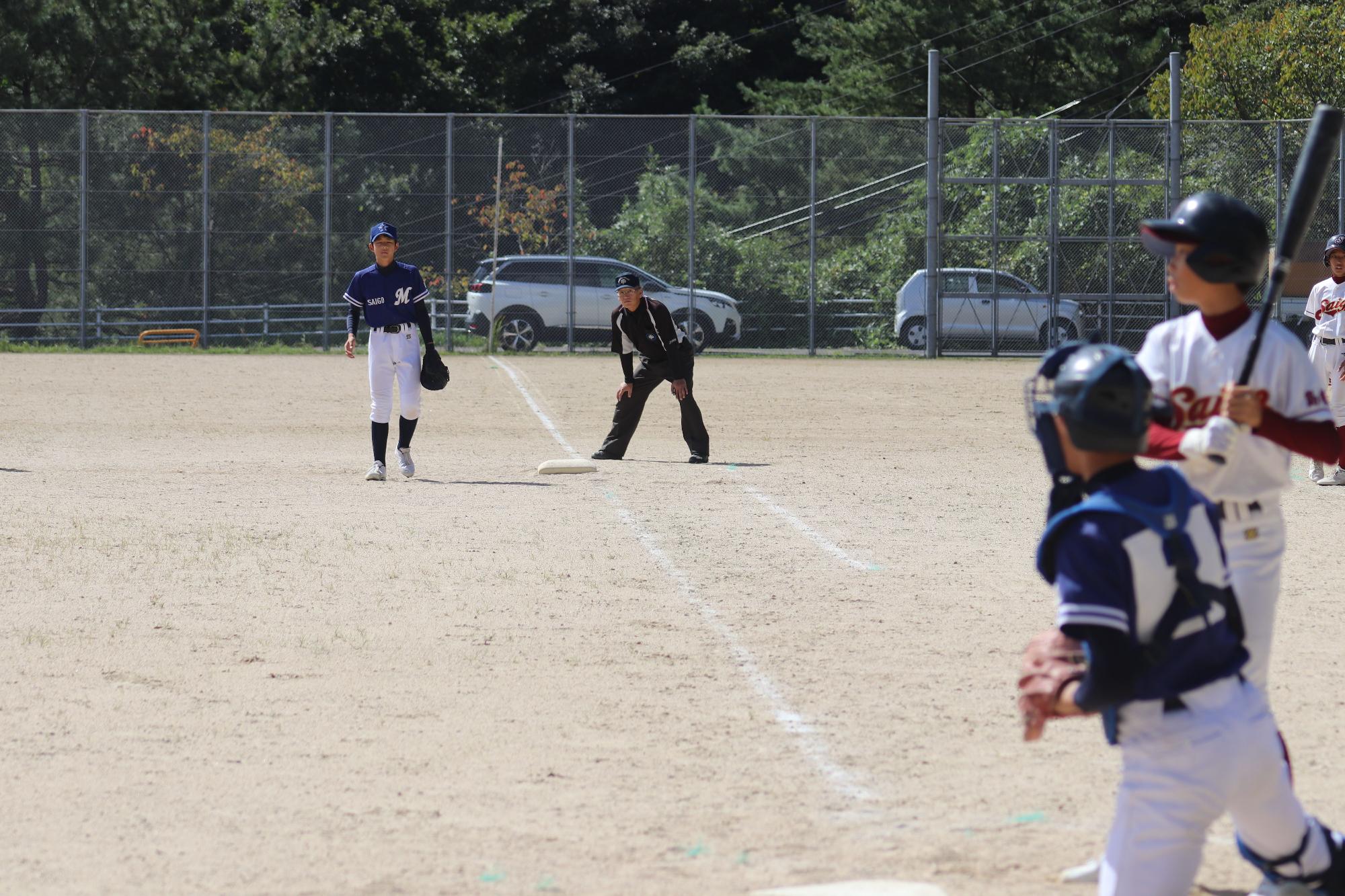 運動場でユニフォーム姿の生徒たちが、野球の試合をしている写真