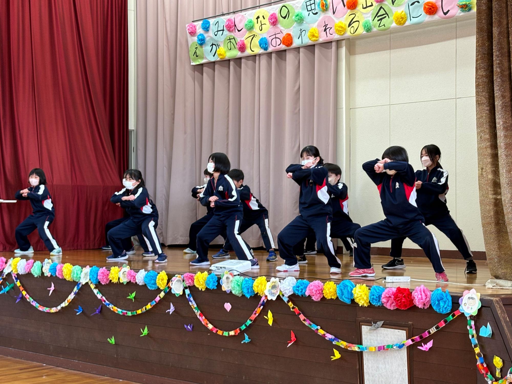 体育館の舞台上で児童たちがダンスを披露している場面の写真