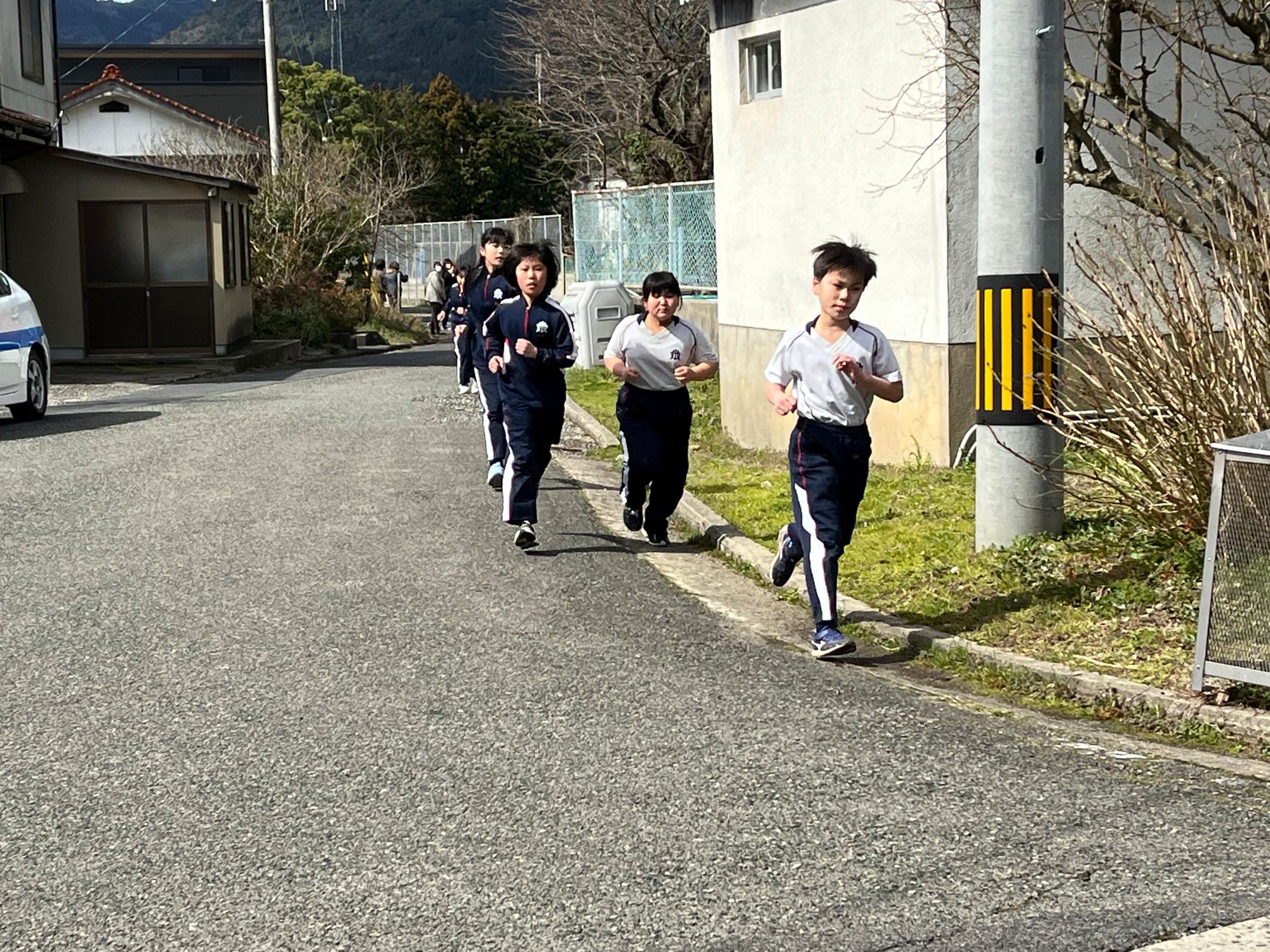 学校近くの道路で児童たちがランニングをしている写真