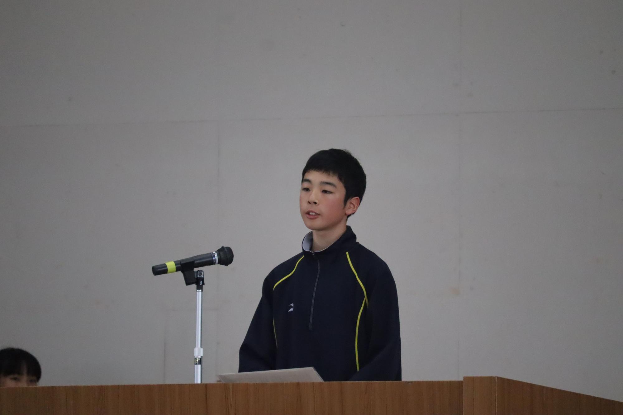 体育館で生徒が壇上で発表をしている写真