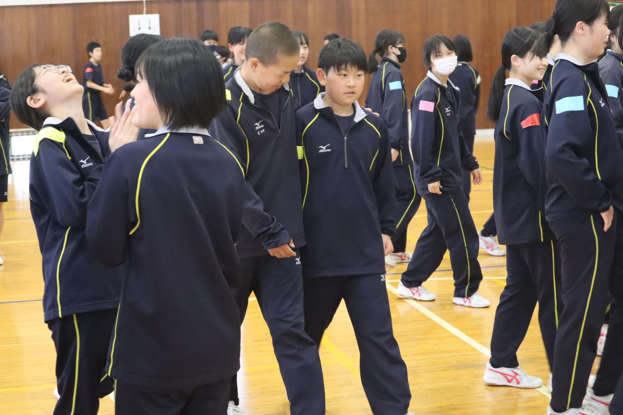 体育館でジャージを着た生徒たちが笑顔で談笑している写真