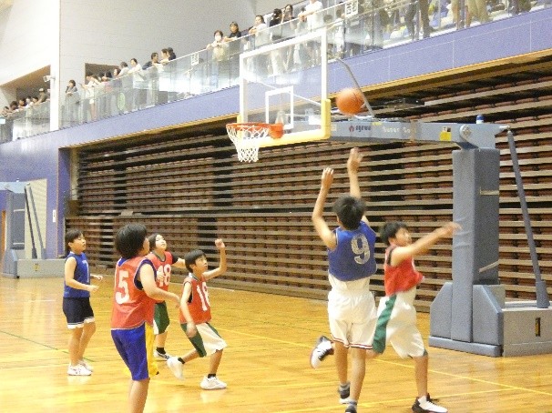 体育館で児童たちがバスケットボールの試合をしている写真