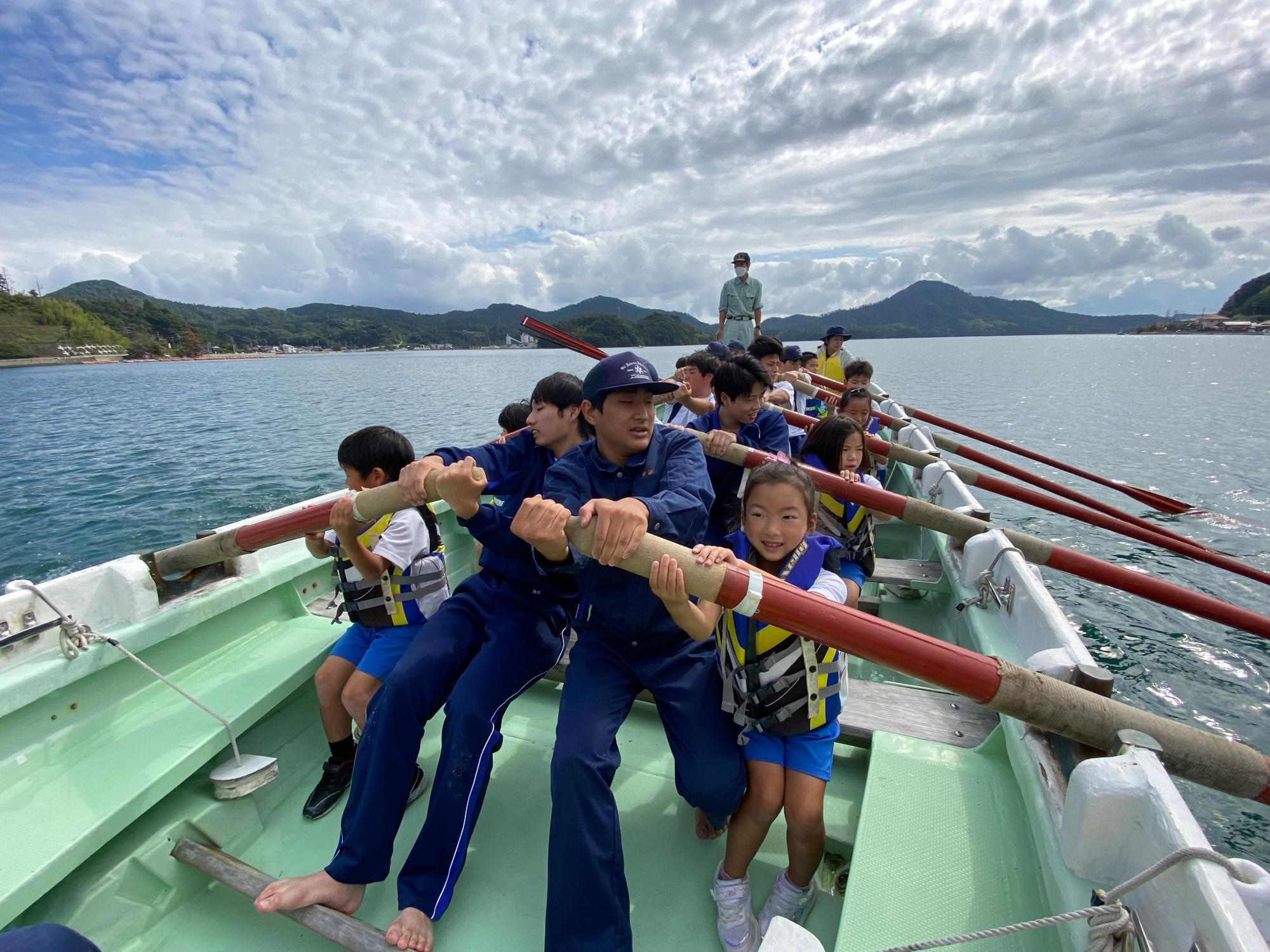 海上で児童たちと生徒たちが力を合わせてクルージングしている写真