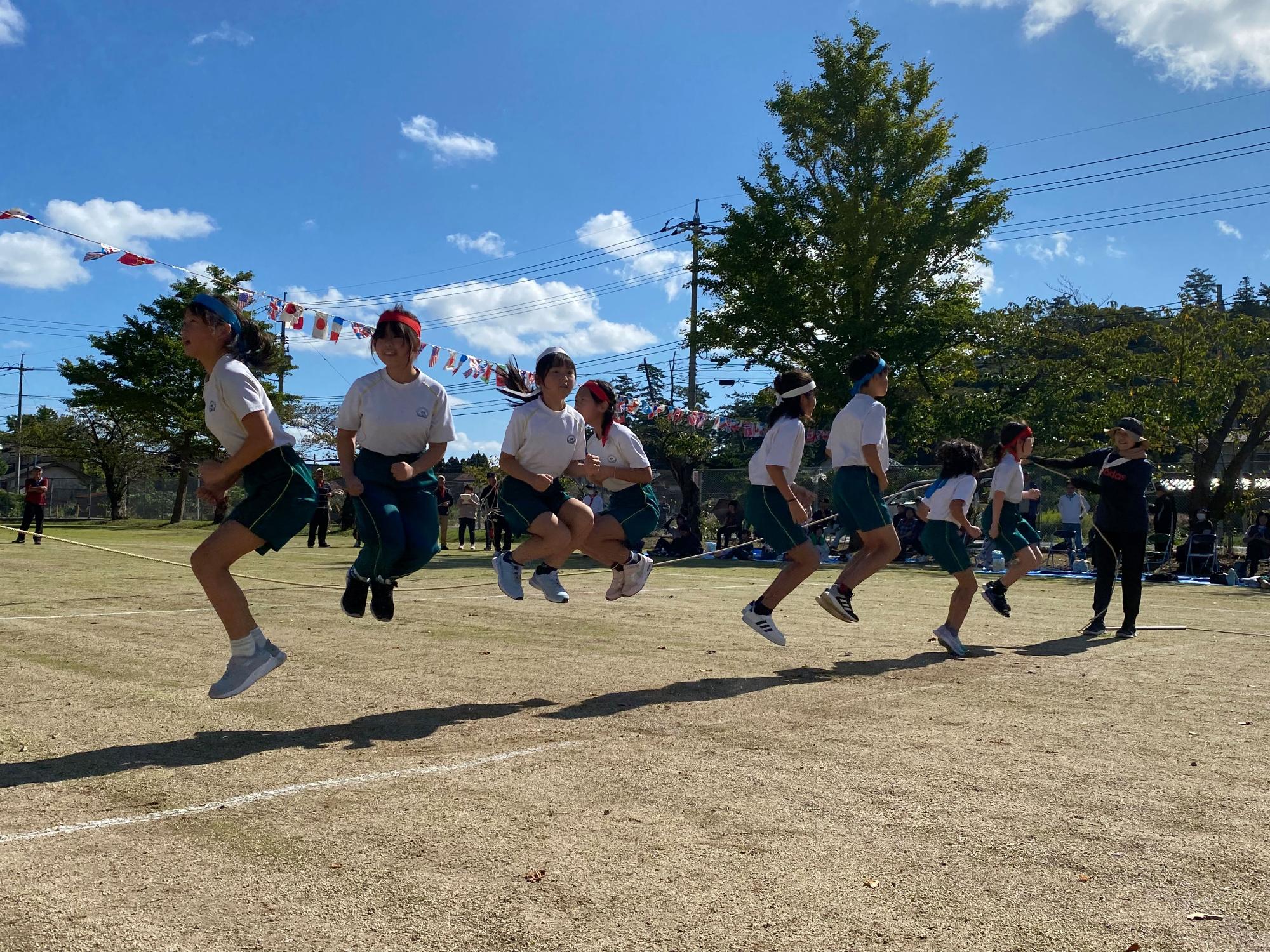 運動場で児童たちが大縄跳びをしている写真