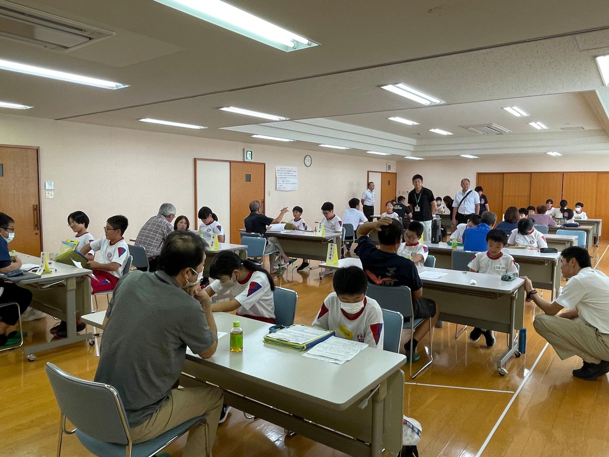 教室で児童たちが大人と向かい合って面談をしている写真