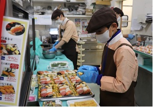 寿司店で盛り付け作業を行う生徒の写真