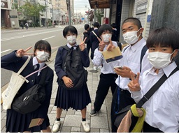 町中で友達と並んでポーズをとる生徒たちの写真