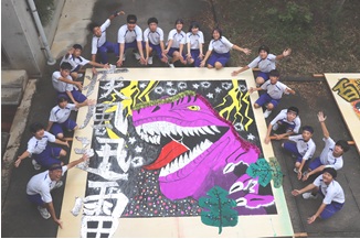 文化祭で恐竜の絵を描いた大きな壁画を囲む生徒たちの写真